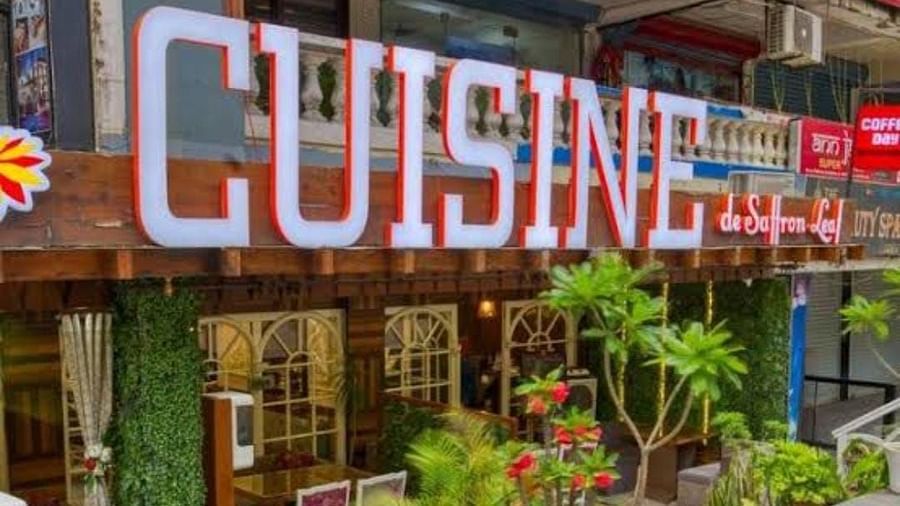  A vibrant restaurant exterior at Cuisine de Saffron Leaf featuring a CUISINE sign, lush plants, and charming architecture.