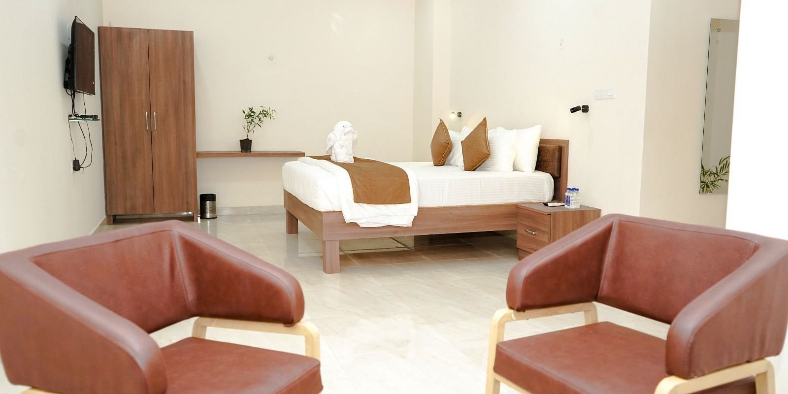 Well-lit room with a double bed and chairs at ANS M Square Hotel & Resort, Kalaburagi