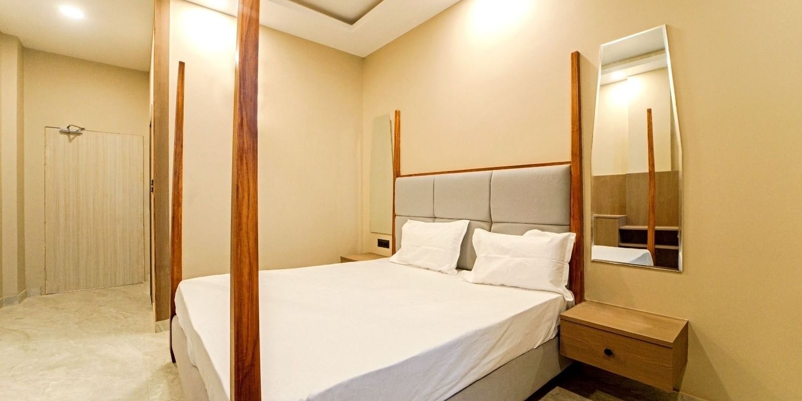 A bedroom at Grassfield Riveria Resort, Jaipur, with a four-poster bed, minimalist decor, and a private bathroom.