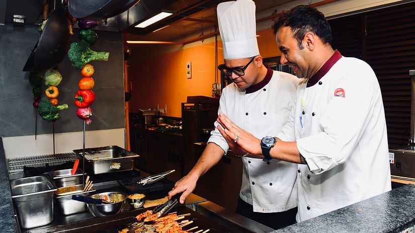 A chef guiding another chef in preparing barbeque at Cloud9 Sarovar Premiere, Palolem Goa.