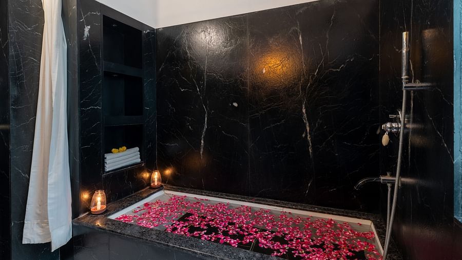 A spacious bathtub filled with water and scattered flower petals at Panna Vilas Palace