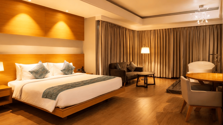 Spacious bedroom featuring a double bed, lounge area, and in-room bathtub at Kiranshree Grand Hotel.