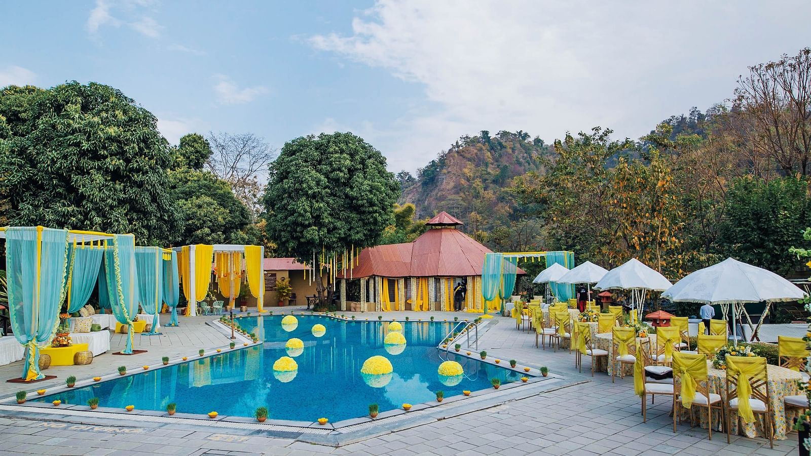 An image of swimming pool decorated with flowers and a seating arrangement made for guests 