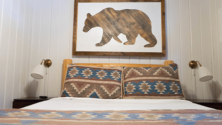 A room with a double bed and an artwork of a bear hung on the wall behind it at Shaver Lake Village Hotel.