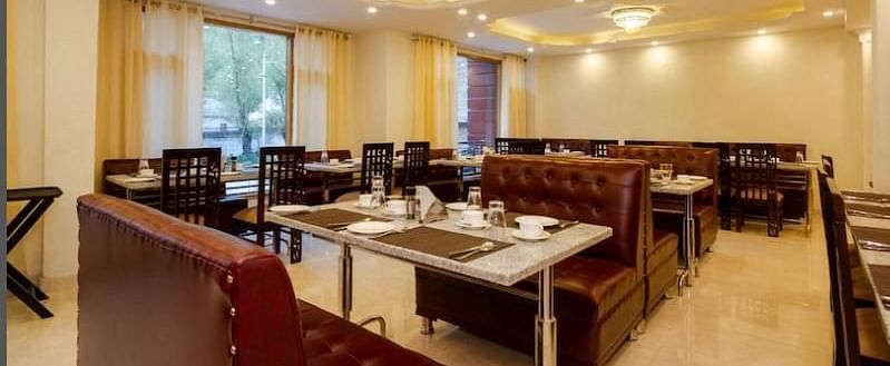 A dining area in La Serene Valley Resort in Manali. The dining room is well-lit and dining tables. | DLS La Serene Manali