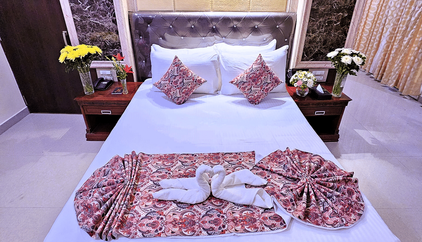 An image of a bedroom with two bedside table on each side - Sathyam Grand Resort 