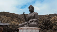 A huge statue of Buddha in a temple surrounded by mountains