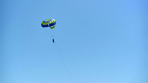Parasailing adventure in Daman with a colourful parachute soaring above the wide sandy shoreline and open coastline
