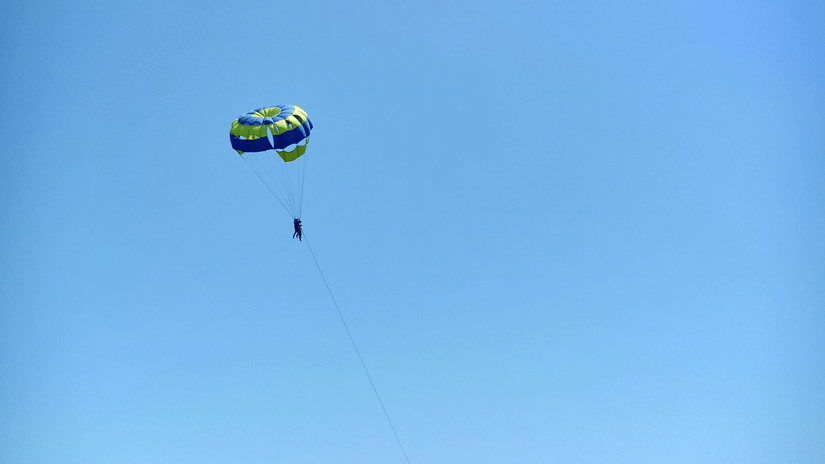 Parasailing adventure in Daman with a colourful parachute soaring above the wide sandy shoreline and open coastline