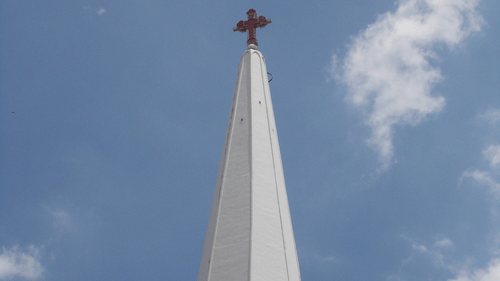 a tall white tower of a church with a cross on top