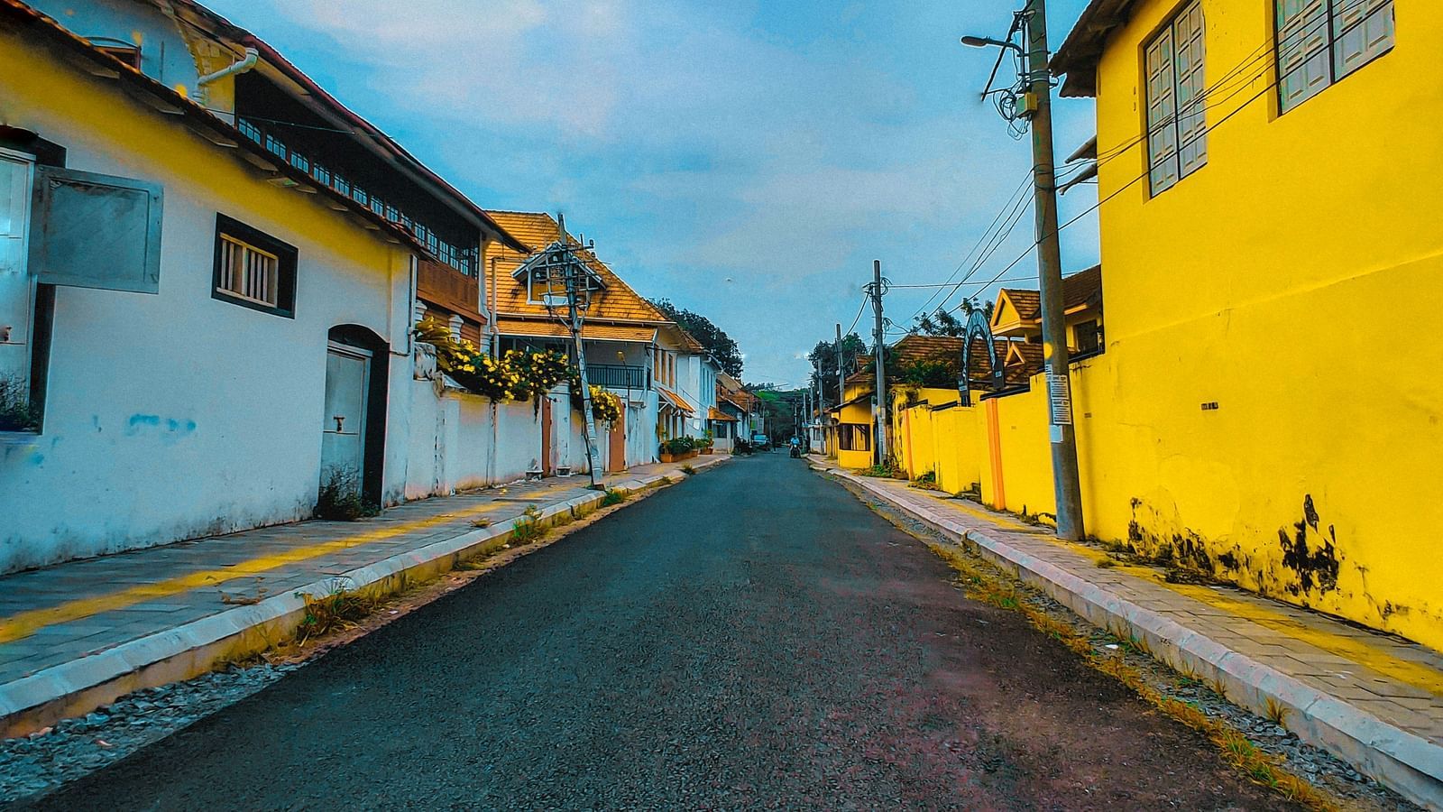 One point perspective of a street with buildings on both sides under a partly cloudy sky
