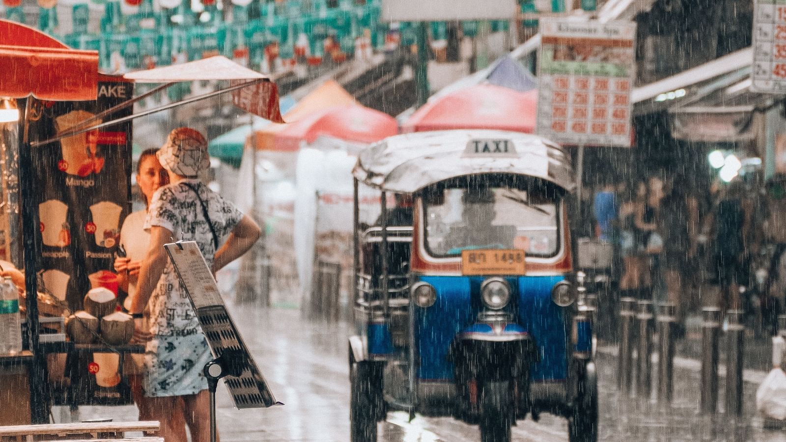 an image of the Khao San Road captured when it is raining and a tuk-tuk can be seen.
