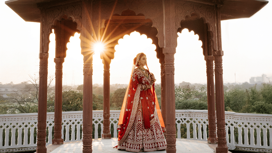 Bride standing under ornate heritage arches at Umaid Palace during golden hour.