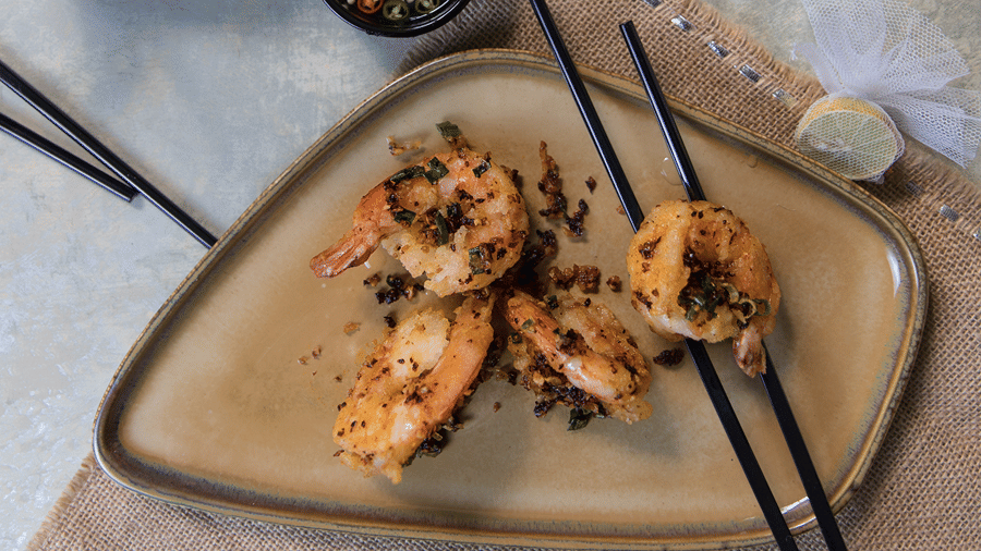 image of a preparation of prawns served with a pair of chopsticks on the plat at the pickwick - The Claridges New Delhi