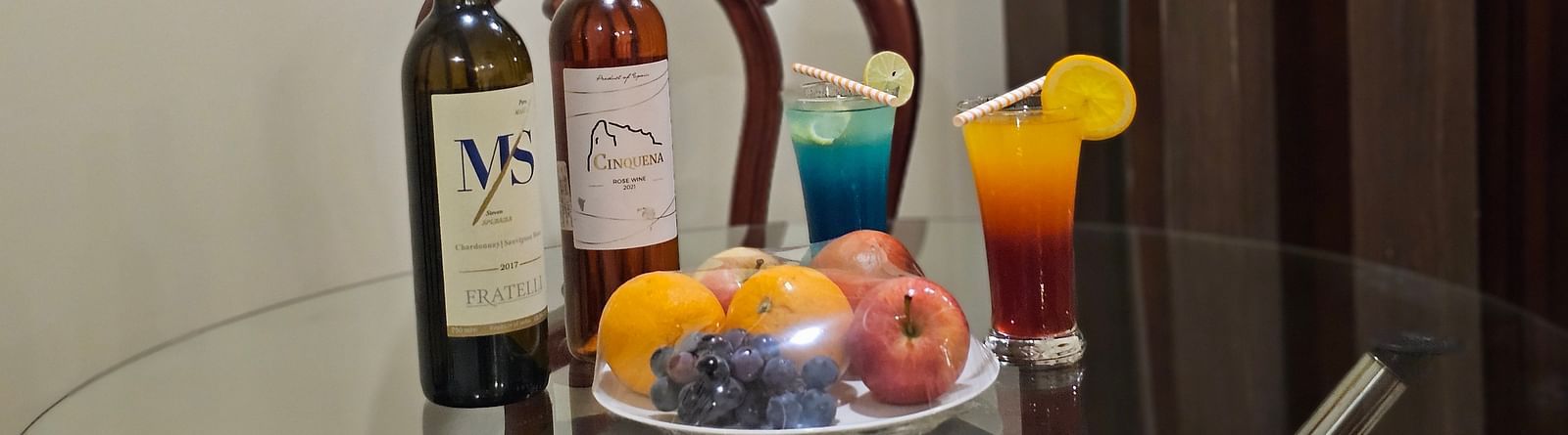An image of a table which has fruits and some bottle placed at the centre - Sathyam Grand Resort