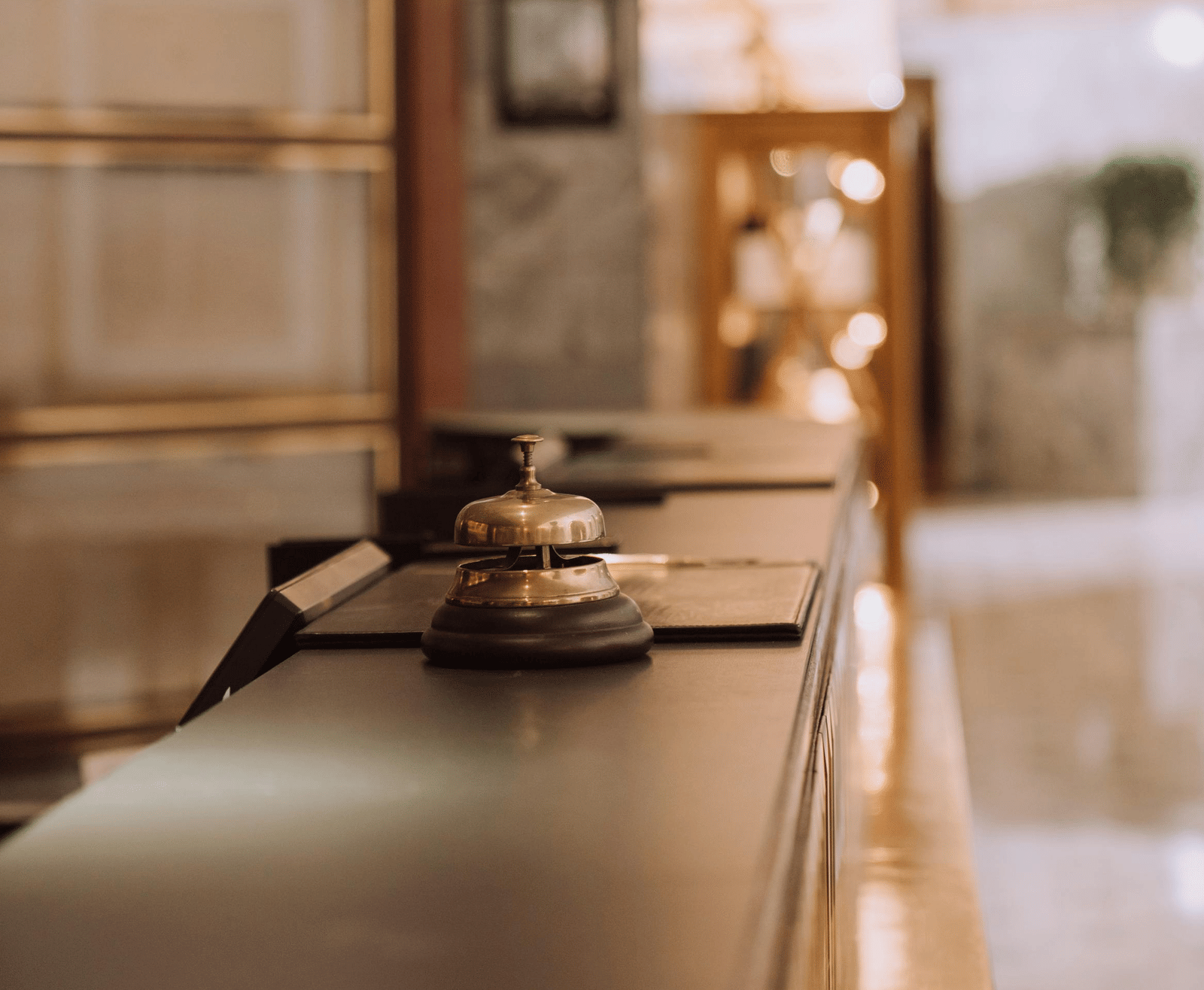 A blurred, modern interior scene, possibly a hotel lobby or restaurant, featuring a dark counter and soft, out-of-focus lighting.
