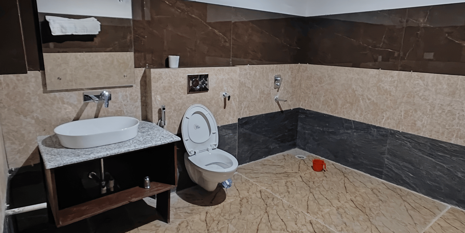 A clean and modern bathroom featuring dark and light brown tiling with a white porcelain vanity at Indus Serenity Retreat.