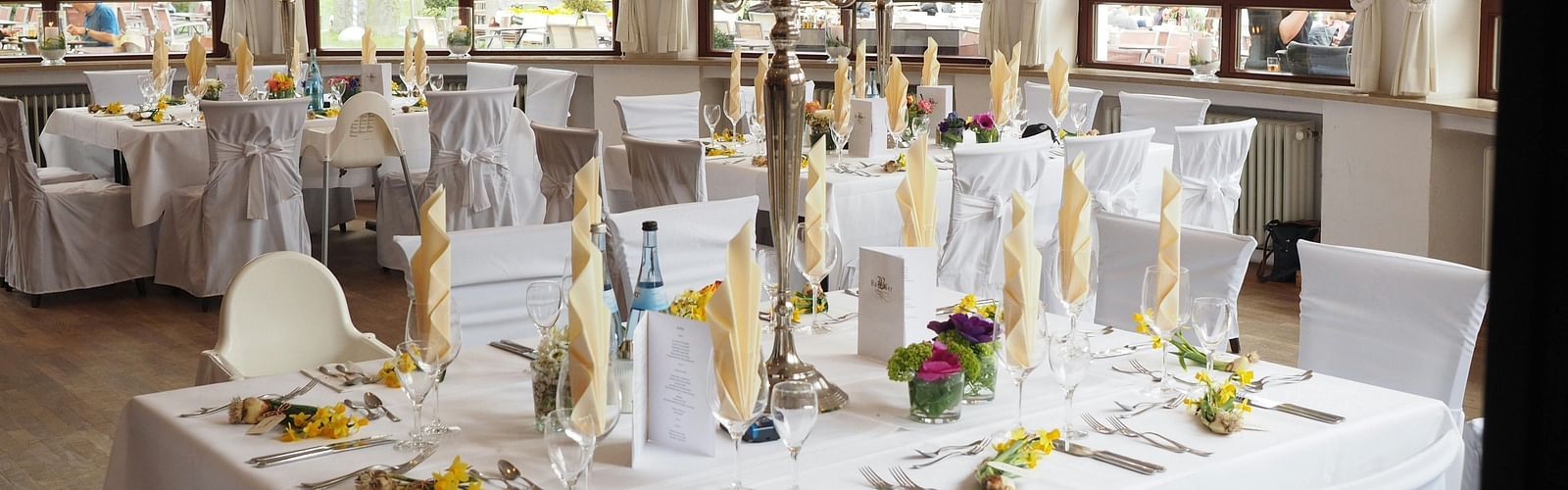 A restaurant depicting seating arrangement with cutlery and decorative items on the table