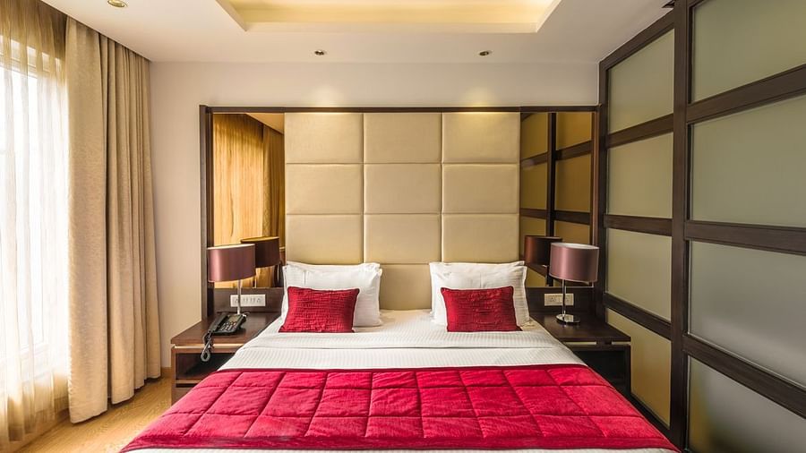 A Hotel bedroom with large bed, red bedspread and padded headboard - TGI Grand Fortuna, Hosur