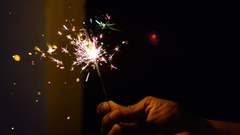 Man lighting a firecracker sparkle with a dark background
