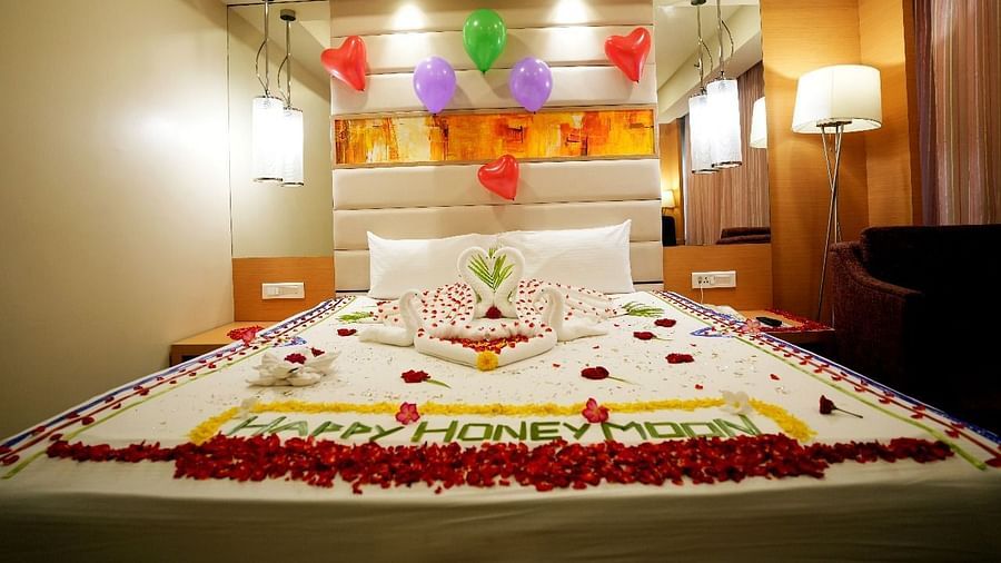 A luxurious hotel room with a beautifully decorated bed adorned with flowers and elegant lighting for Honeymoon
