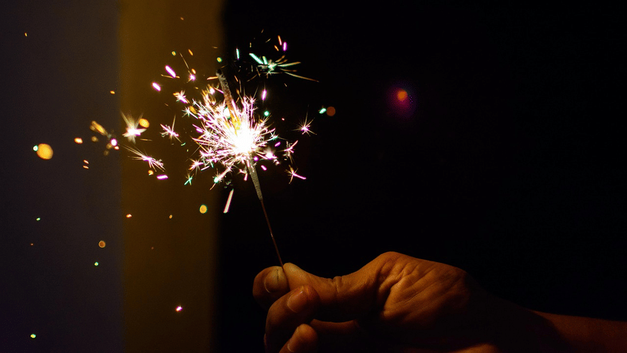 Man lighting a firecracker sparkle with a dark background