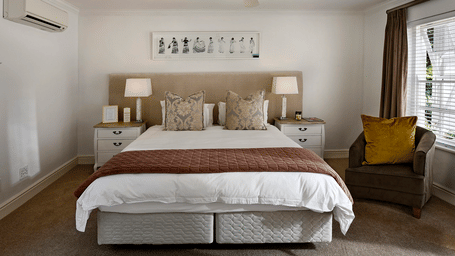 A king size bed with a ceiling fan hanging over it in a bedroom. 