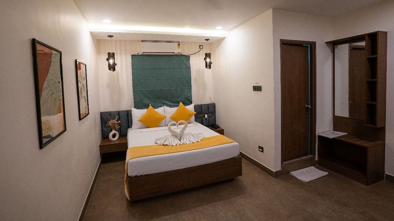 A room with a double bed, decorative pillows, wall art, and warm lighting, offering a welcoming atmosphere at Hotel Kyzen Smartstays – Smart, Reliable, Kyzen