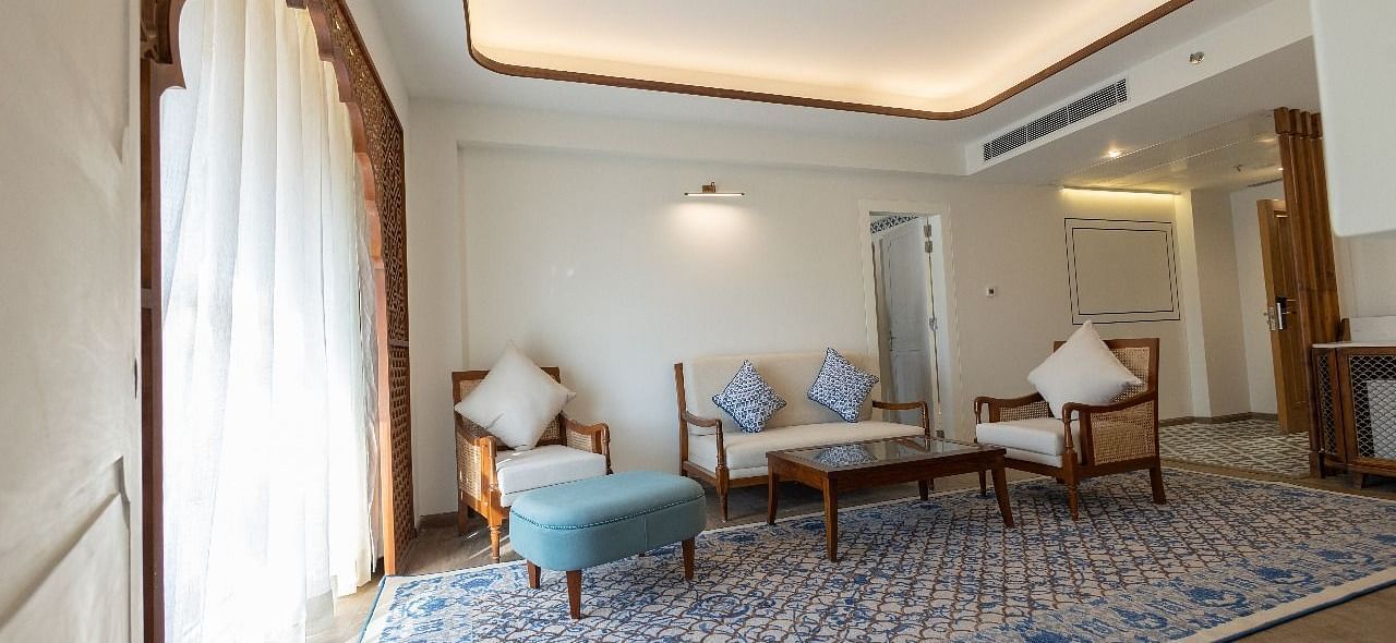 Natural light coming from the arched balcony covered with white linen curtains in the living area of the Ananta at Bhagirathi by RDB Atishay.