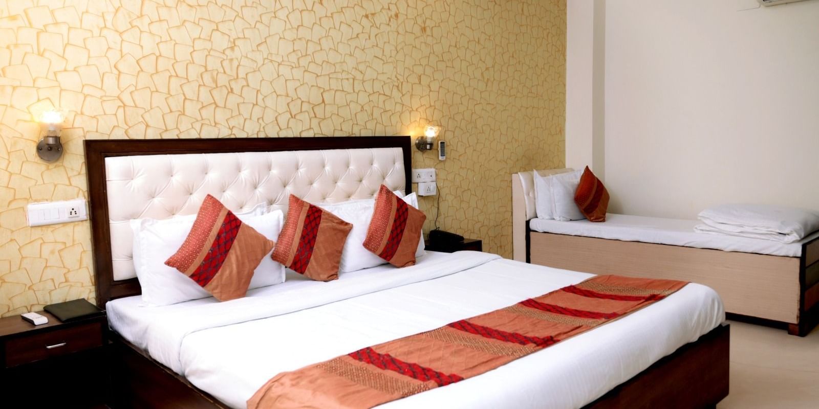 A classy space featuring a king-size bed and a single bed, warm lighting, and a contemporary design.