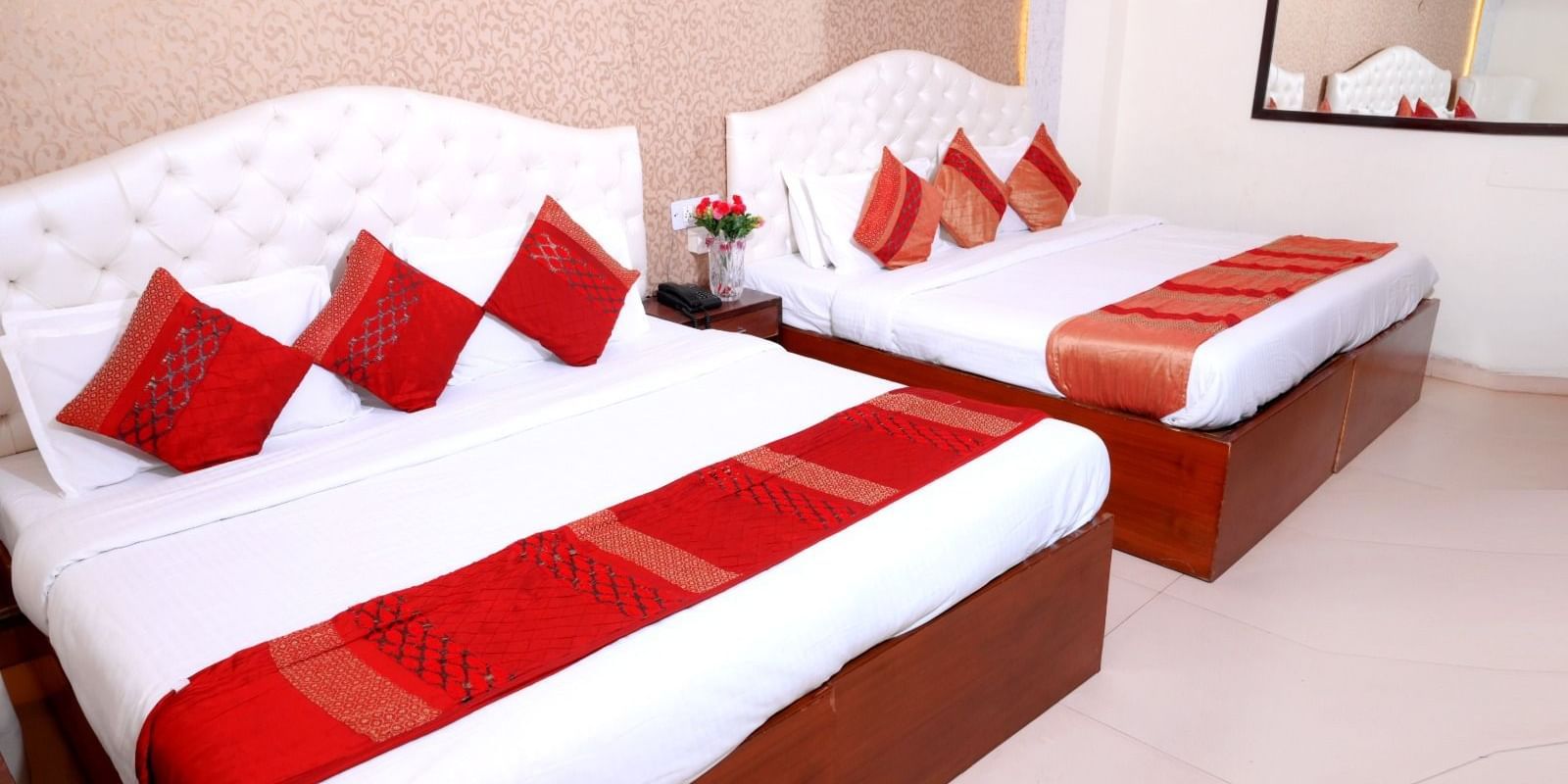 Spacious family room at Hotel Diamond Inn, Chandigarh, with two double beds and coordinated red decor.