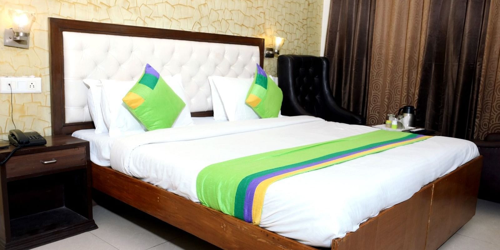 A modern hotel room with a king-size bed, green and white bedding, golden accent wallpaper, and warm lighting - Hotel Diamond Inn, Chandigarh