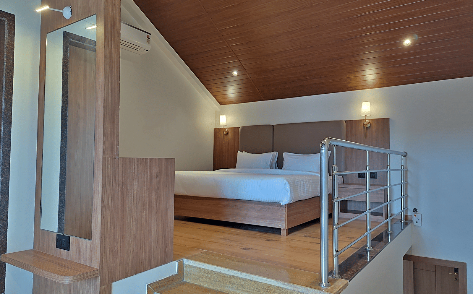 Bedroom with a double bed, wooden furnishings, loft area, and railing.
