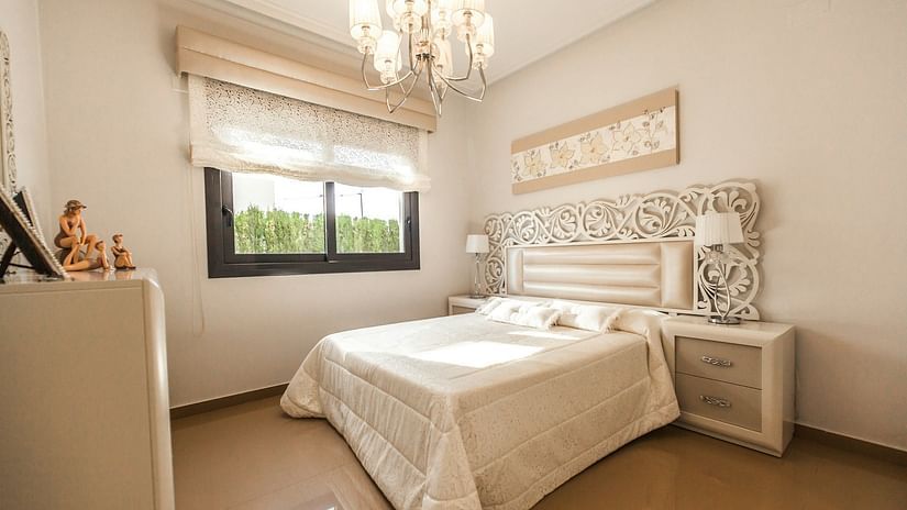 A cozy bedroom with a comfy single bed with soft pillows, a rolling curtain window, a small bedside table, and a fancy chandelier that makes the room look grand - Hotel Lalita Grand