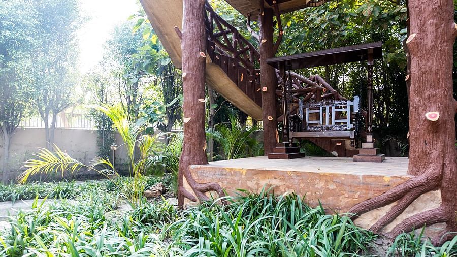 An image of a cosy wooden structure surrounded by a garden.