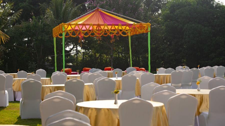 An outdoor event space under a red and yellow tent, with round tables and chairs on a lawn | Citrus Garden | Grand Bay Resort and Spa