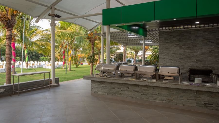 An outdoor catering setup under a large tent, with long buffet tables laden with food warmers | Citrus Garden | Grand Bay Resort and Spa