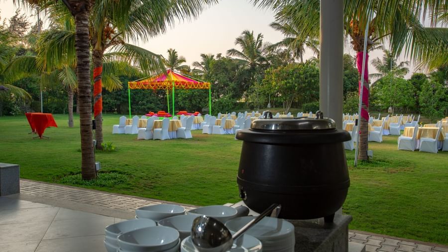 An outdoor catering station on a green lawn with palm trees, featuring a large black soup pot | Citrus Garden | Grand Bay Resort and Spa