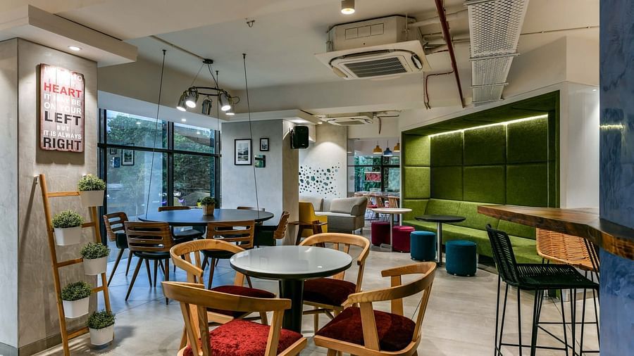 Shared workspaces with tables and chairs set up in various sections of the area at Indie Stays, BKC Kalina.