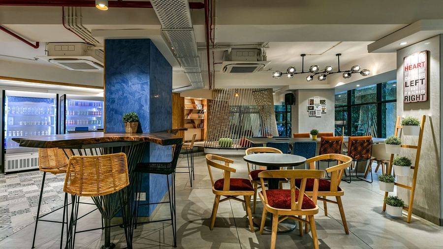 Common workspaces with tables and chairs arranged in different sections of the area at Indie Stays, BKC Kalina.