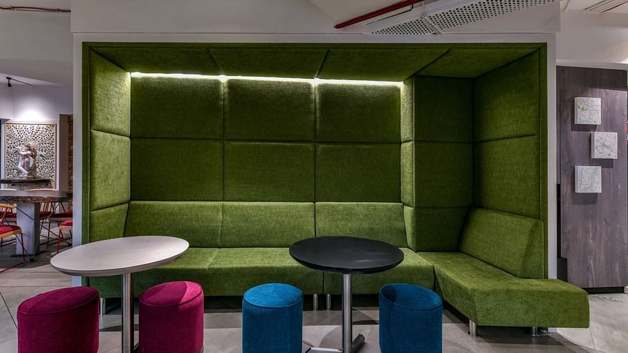 Large cushioned booth seating with a round table, alongside cylindrical cushion seating, at Indie Stays, BKC Kalina.