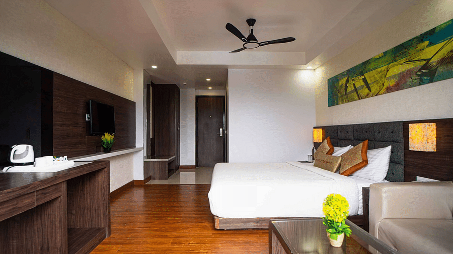 A hotel room at Mansha Hotel Regency with a large bed, wooden flooring, and a ceiling fan.