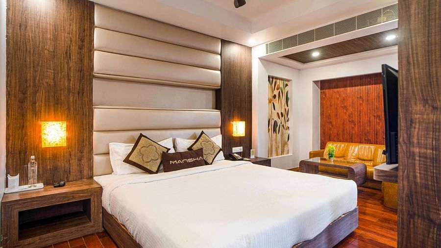 A room at Mansha Hotel Regency featuring a bed with a large headboard, bedside table, and other room amenities.