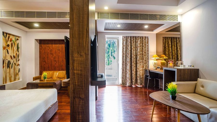 A room with a bed on side of the partition and the other side showcases a sofa, a coffee table, and more amenities at Mansha Hotel Regency.