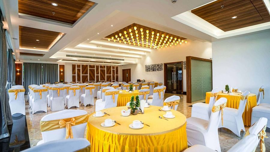 A brightly lit banquet hall at Mansha Palace is elegantly prepared for an event with round tables and draped chairs.