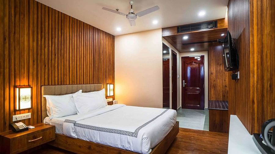 A cozy bedroom at Mansha Palace features wooden paneling, a comfortable bed, and a ceiling fan.