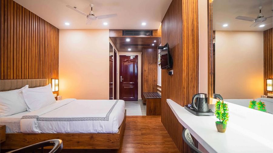 A well-furnished room at Mansha Palace offers a comfortable bed, wooden walls, a mirror, and a beverage station.
