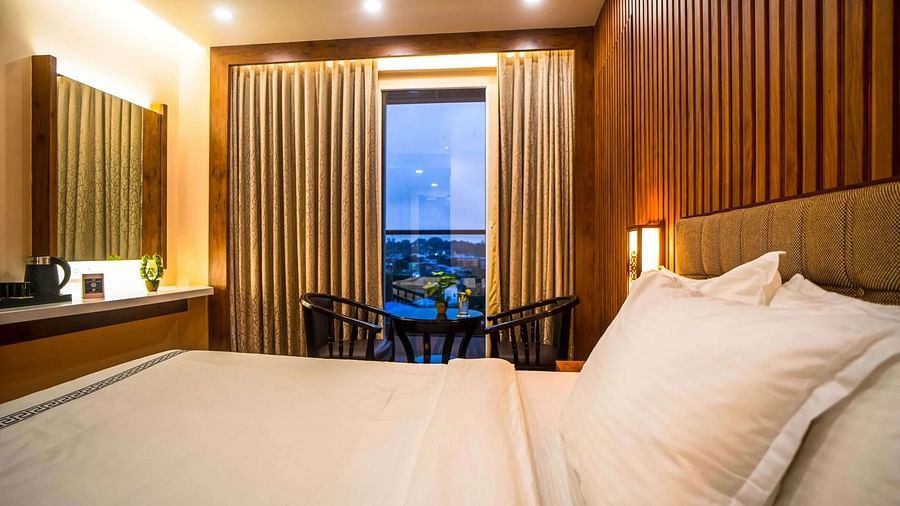 A comfortable bedroom at Mansha Palace features a cozy bed, wooden walls, and a small seating area by the window.