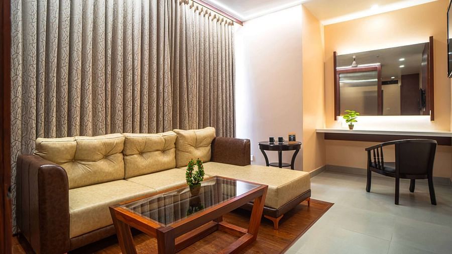 A comfortable living area at Mansha Palace features a plush sofa, a glass-topped coffee table, and a vanity with a mirror.