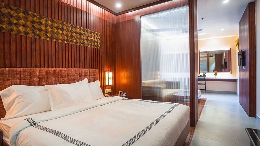 A stylish bedroom at Mansha Palace features a comfortable bed and a partial view into an adjacent area with a desk.